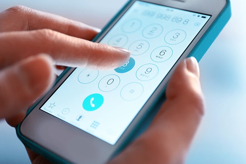 Close-up of a hand using touchtone input on a smartphone to interact with an IVR system for customer service