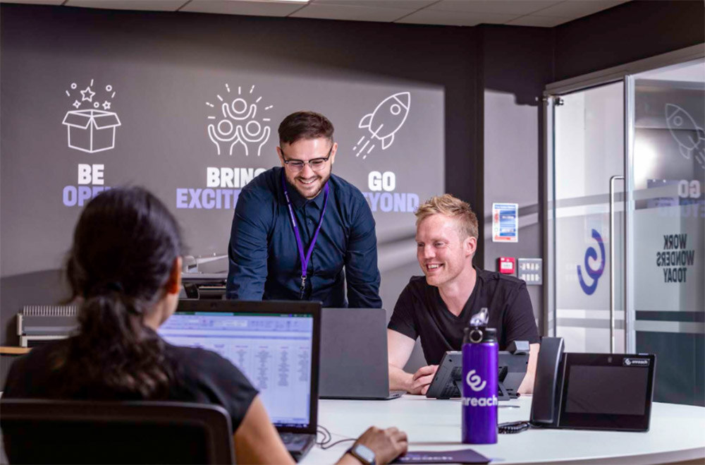 Team members at Enreach collaborating at a desk, using Enreach's customer service tools